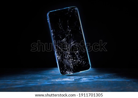 Mobile cellphone with broken glass. Smartphone falling down on the ground and broke touchscreen with beauty blue backlight and dark background