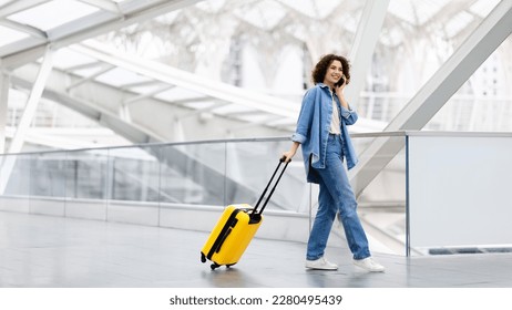 Mobile Communication. Happy Young Woman Talking On Cellphone At Airport, Beautiful Smiling Lady Walking With Luggage At Terminal Hall And Enjoying Pleasant Phone Conversation, Copy Space - Powered by Shutterstock