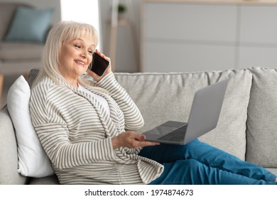 Mobile Communication. Smiling Mature Woman Talking On Smartphone And Working On Laptop At Home Office, Positive Senior Lady Using Computer And Having Pleasant Phone Conversation, Sitting On Couch