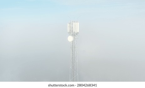 Mobile communication tower emerging from dense morning fog