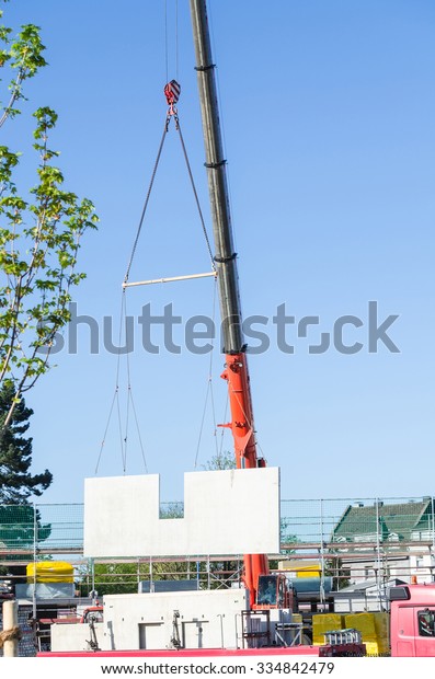 Mobile Crane car on a construction site. Lifts up a\
concrete wall.