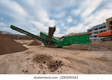 Mobile crushing and sorting complex works among soil piles - Shutterstock ID 2282096561
