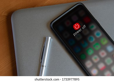 A mobile device powering down, resting on a laptop - Shutterstock ID 1733977895