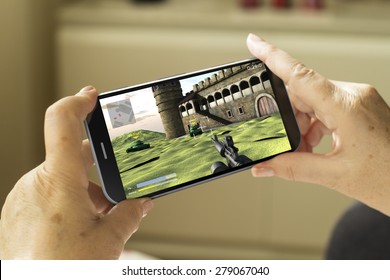 Mobile Gaming Concept: Mature Woman Hands With A 3d Generated Smartphone With Game On Screen