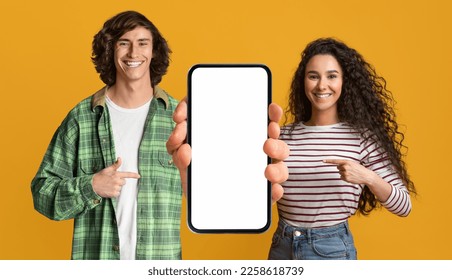 Mobile Mockup. Happy Young Couple Pointing At Cellphone With Blank White Screen, Millennial Man And Woman Showing Copy Space For Online Advertisement, Posing Over Yellow Background, Mockup - Shutterstock ID 2258618739