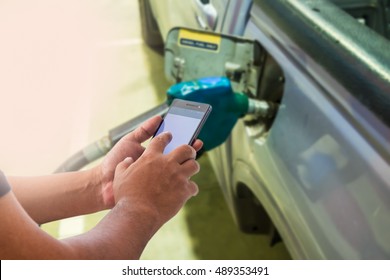 Mobile payment, Cashless society concept. Man using smart phone with blank  screen in gas station.