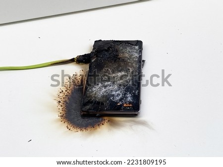 Mobile phone after battery explosion. Smartphone burn. Mobile phone caught fire. Mobile smartphone overheat and catch fire. Cable overheat and catch fire. Smartphone burn, bang, blast, blowing up.