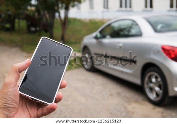 Mobile phone apps for car owners concept. Man\
using smart phone to check status, control his new car. Blank Empty\
mobile phone screen for\
design