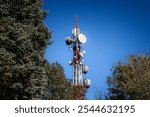 Mobile phone base station, equipped with 3G, 4G and 5G antenna, at top of a European forest in serbia with blue sky, used for cellular phone network coverage, reception  transmission.