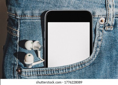 Mobile phone with blank mockup screen in the pocket of blue jeans with headphones