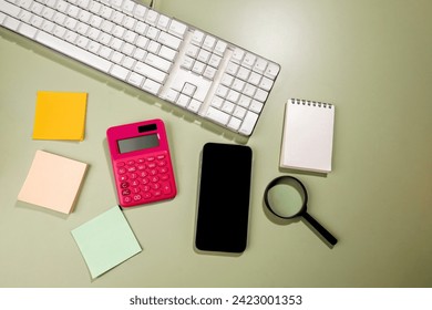 Mobile phone with blank screen and an empty notebook and note paper with magnifying glass and calculator on a colored background. Blank mobile phone screen and empty notebook with note paper for copy  - Powered by Shutterstock