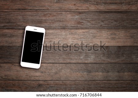 Mobile phone with blank screen on wooden table background. Smartphone on wood old plank vintage texture background. top view, copy space