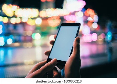 Mobile Phone With Blank Screen In Woman's Hand On Background Festively Illuminated City