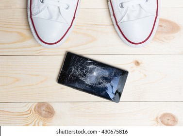 Mobile Phone With Broken Screen On Wooden Floor