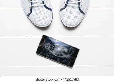 Mobile Phone With Broken Screen On White Wooden Floor