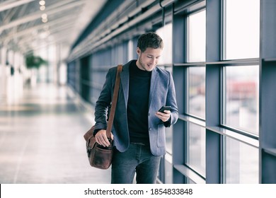 Mobile Phone Business Man Walking In Airport With Messenger Bag Using Cellphone Texting Sms Message On Smartphone App - Businesspeople Commute Lifestyle. Young Professional Businessman.