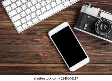 Mobile phone, camera and computer keyboard on wooden background. 
