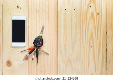 Mobile phone and car remote keys on wooden background