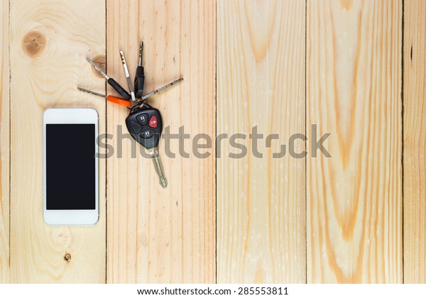 Mobile\
phone and car remote keys on wooden\
background