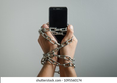 Mobile phone chained to the hands of a man, telephone dependence - Shutterstock ID 1095560174