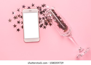 Mobile phone and champagne glass with silver stars confetti on pink color paper background minimal style - Powered by Shutterstock