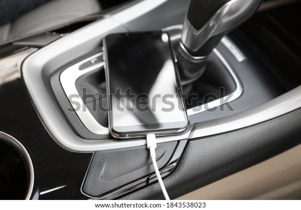 Mobile phone\
with charging cable in car,\
closeup