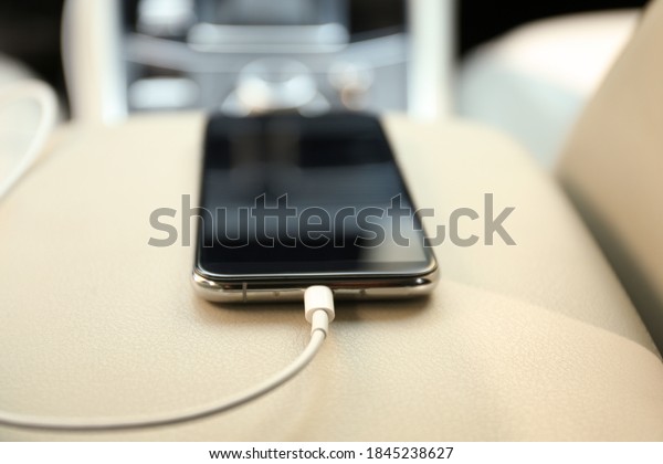 Mobile phone\
with charging cable in car,\
closeup