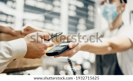 A mobile phone with contactless technology in a restaurant. A male customer pays the bill via a smartphone using NFC technology. Close-up of a mobile payment hand in a cafe.