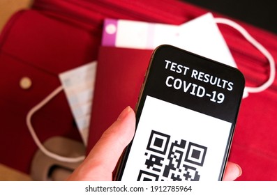 Mobile phone with a digital vaccination certificate near passport and suitcase before travelling. Preparing for a trip after Covid-19 vaccination. Safe travel, new normal. - Powered by Shutterstock