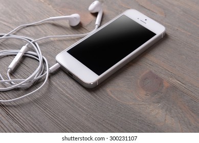 Mobile phone and earphones on wooden background - Powered by Shutterstock