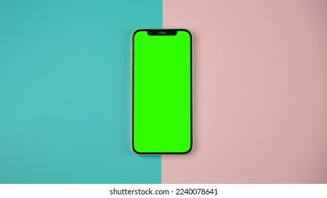 Mobile phone with empty blank green screen flat lay, Smartphone isolated on blue and pink colour background - Powered by Shutterstock