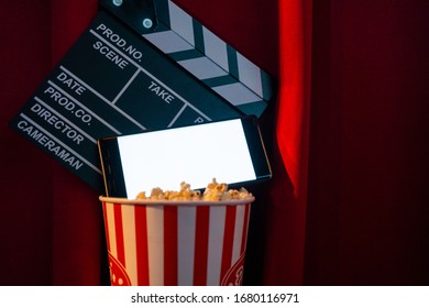 mobile phone with empty white bright screen with popcorn bucket and movie clapper board. Concept of streaming TV on internet phone.