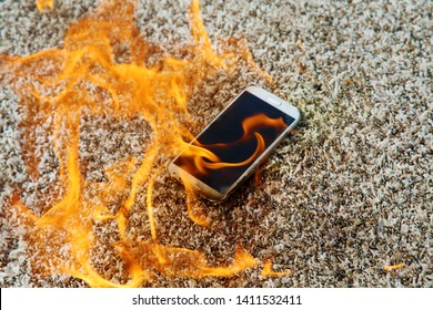 Mobile phone explodes and burns. Cell Phone explosion and fire on a beige carpet. Smart Phone Danger from over use or bad manufacturing. Burning up my phone concept. 

