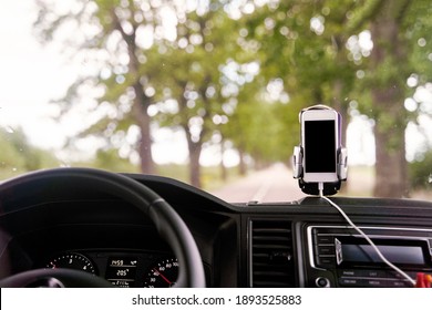 Mobile phone with GPS card in the car. A white smartphone on a stand in the car is used for navigation. High-quality photo