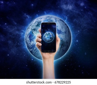 Mobile Phone In Hand - Hand Holding Smart Phone Or Cell Phone On Planet Earth. Life Style, Technology, Communication, Environment And Saving The World Concept. Background Original Image From NASA.gov