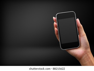 Mobile phone in hand on black background - Shutterstock ID 88215622