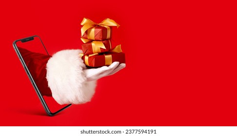 Mobile phone and hand of Santa Claus with Christmas gifts on red background with space for text