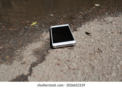 Mobile Phone Lying On Pavement In Puddle