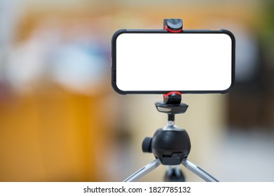 A mobile phone mounted on a tripod for teaching students online.