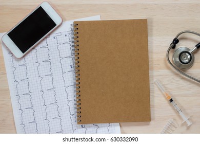 Mobile Phone, Note, Stethoscope,   Syringe, ECG On Wooden Background