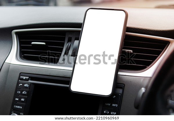 Mobile phone on the car air vent.Blank with\
white screen.Mock up smart phone in\
car.