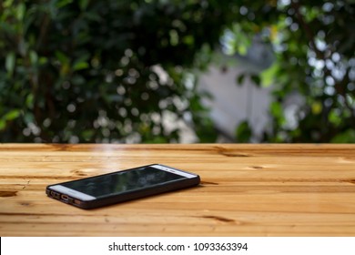 Mobile phone on the wood table in the park 