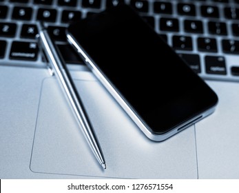 Mobile Phone And Pen On Laptop