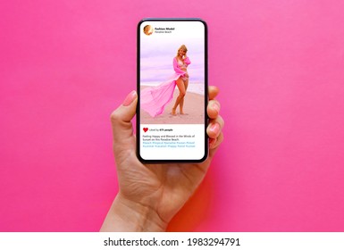 Mobile phone with photo of beautiful model in pink dress on pink background