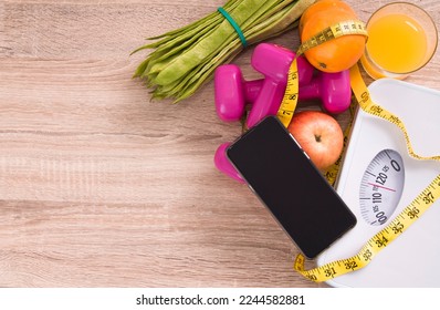 mobile phone, scale, dumbbells and vegetables, diet and technology concept - Powered by Shutterstock