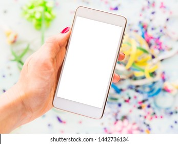 Mobile Phone Screen In Woman's Hand Above Table With Party Streamers And Confetti. Bright Colors.