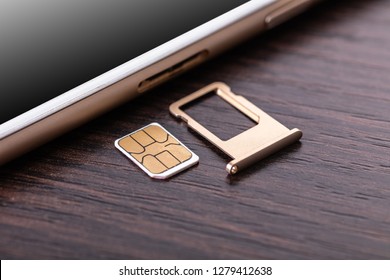 Mobile Phone And Sim Card On A Wooden Background