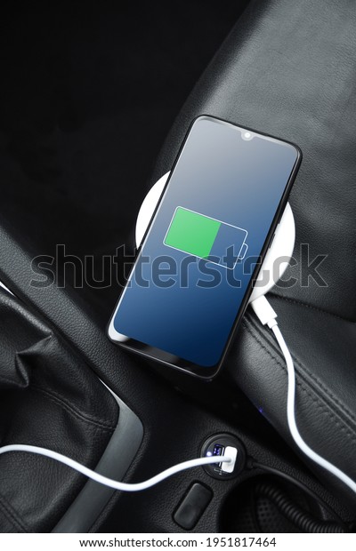 Mobile phone ,smartphone, cellphone is charged\
,charge battery with usb charger in the inside of car. modern black\
car interior.