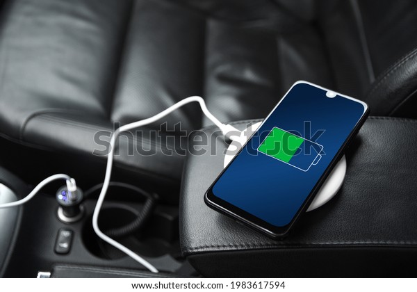 Mobile phone ,smartphone, cellphone is charged\
,charge battery with usb charger in the inside of car. modern black\
car interior.