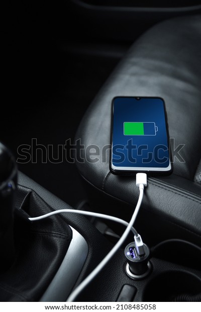 Mobile phone ,smartphone, cellphone is charged
,charge battery with usb charger in the inside of car. modern black
car interior.